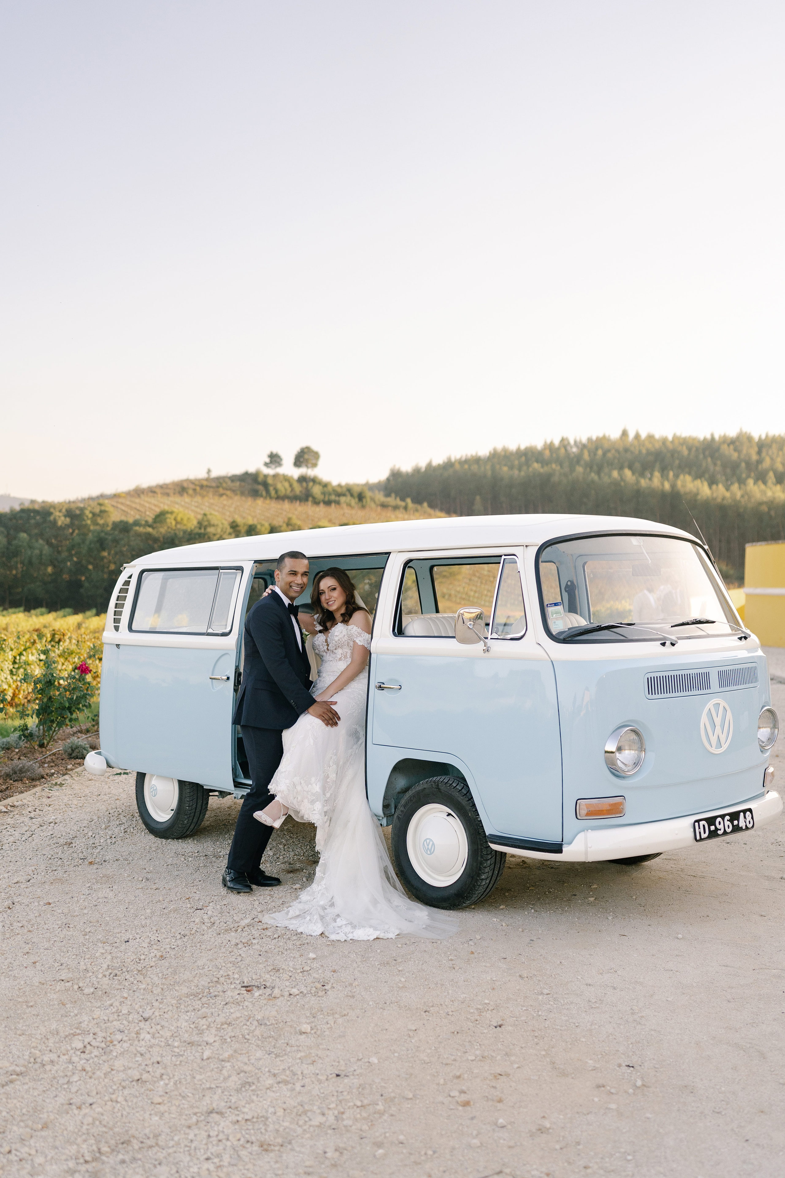 Bride and groom embracing by vintage blue VW van at vineyard wedding in Portugal Bride and groom embracing by vintage blue VW van at vineyard wedding in Portugal