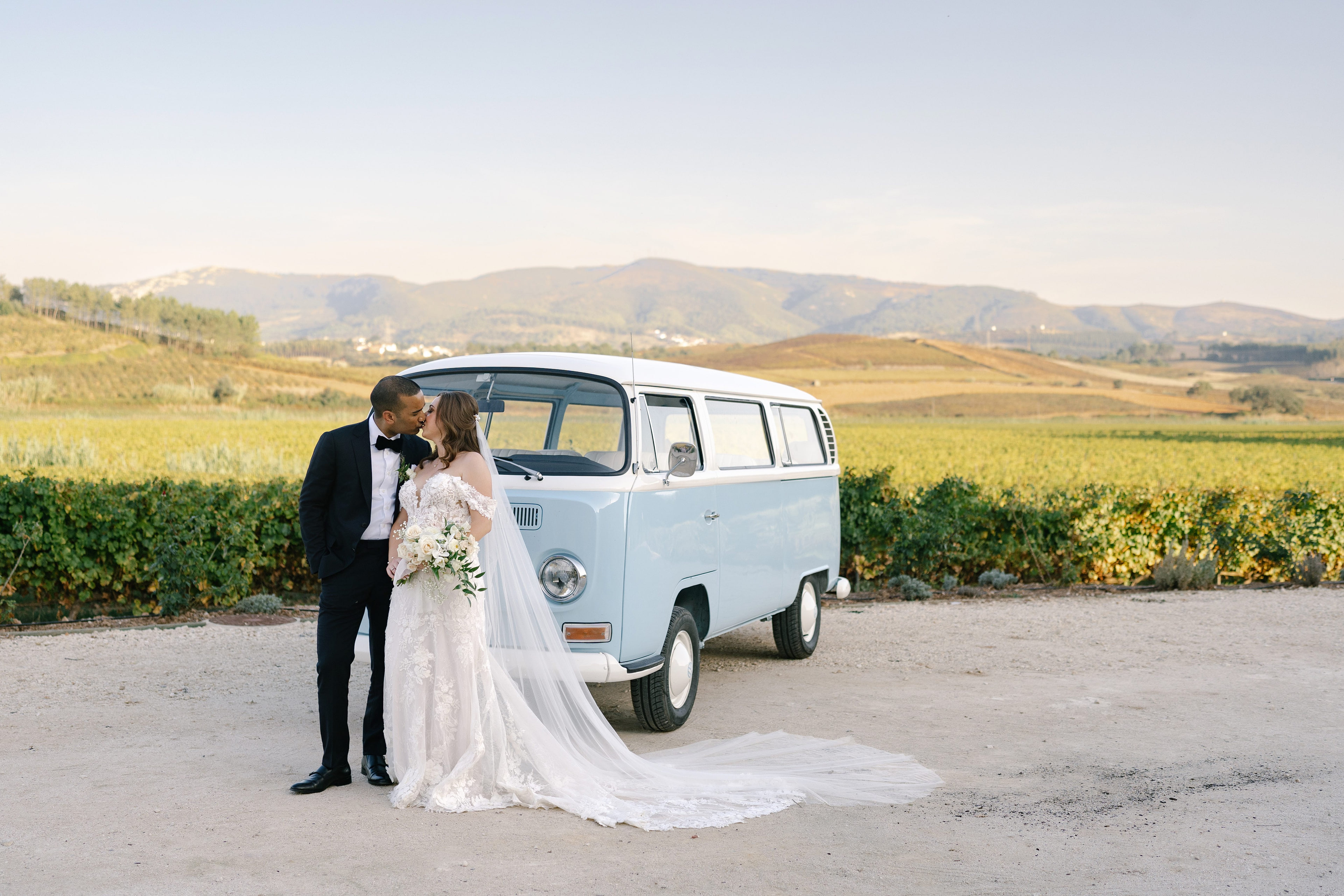 Bride and groom beside a blue vintage van among the vineyards of Quinta do Gradil