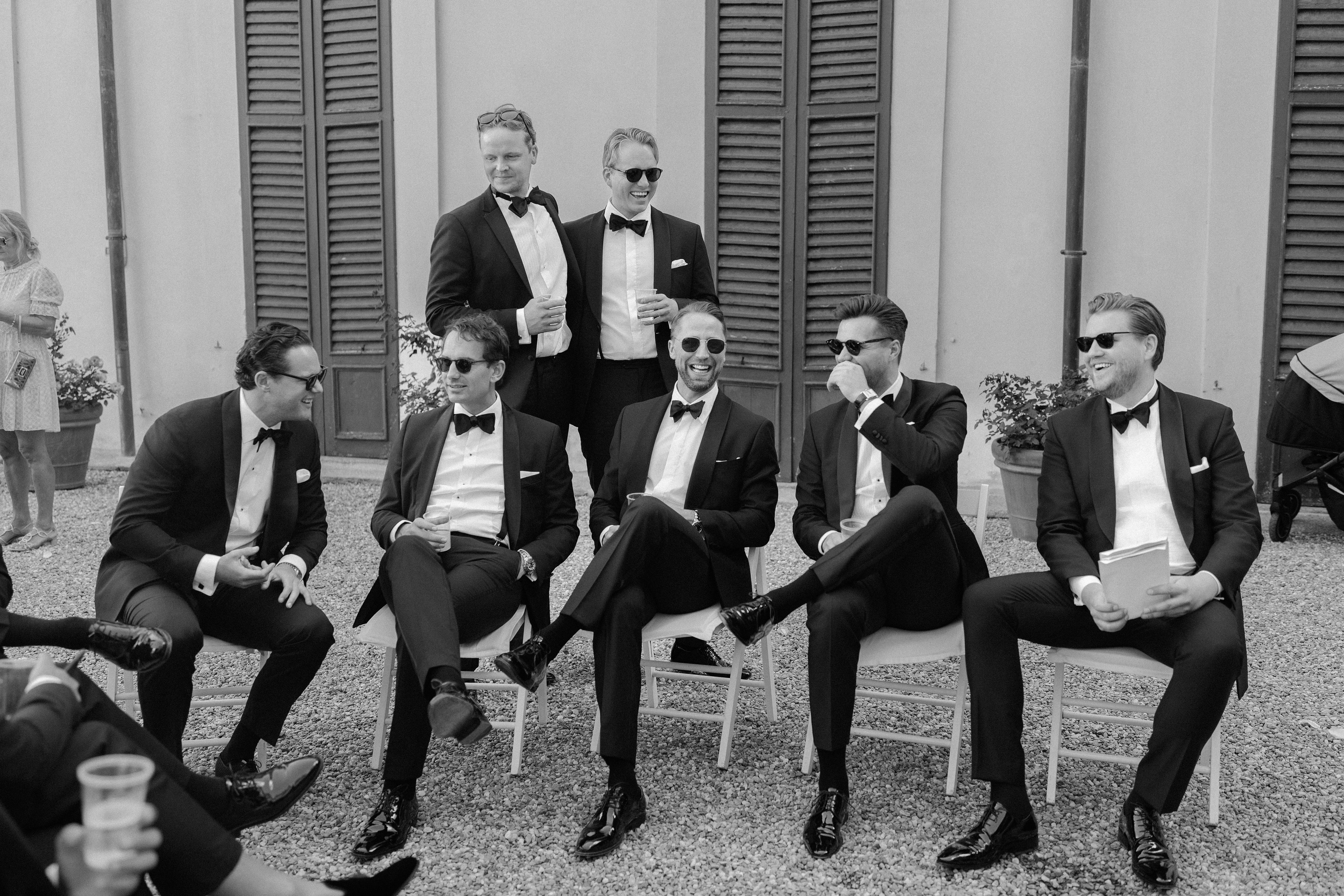 Groomsmen laughing together outside Villa Carlotta, Lake Como, in black and white