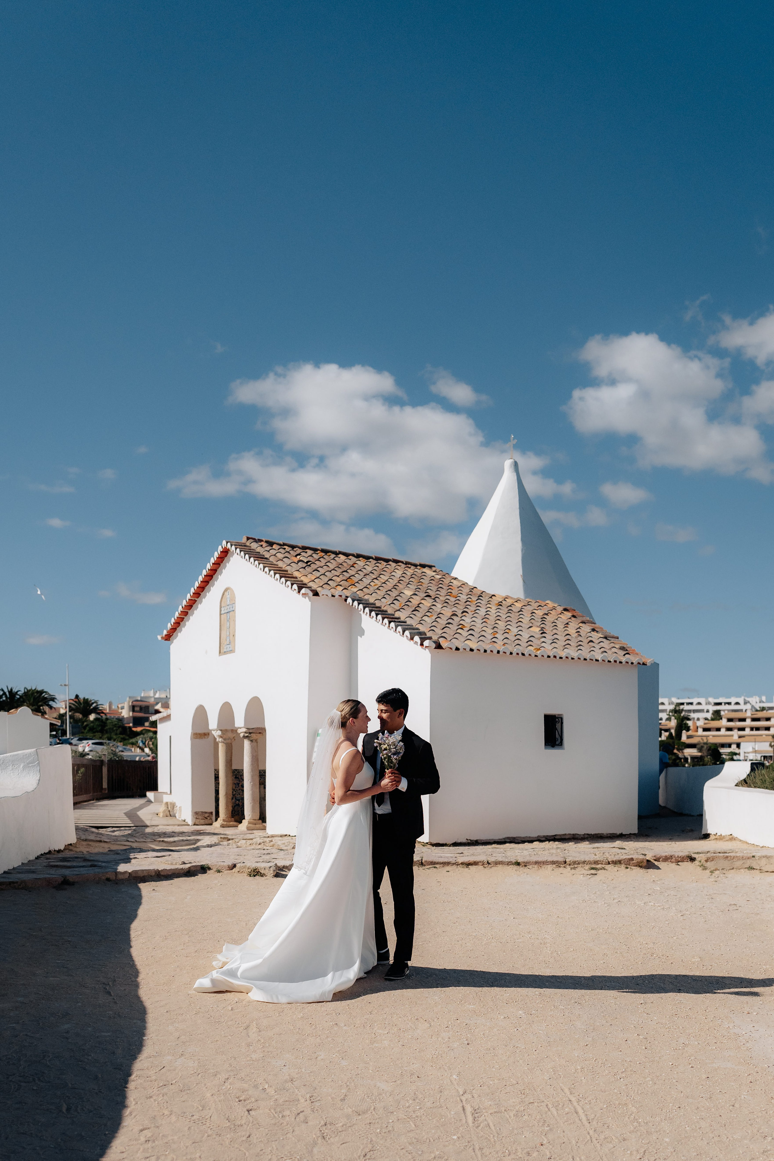 Bride and groom by the white chapel of Nossa Senhora da Rocha on the cliff, Porches, Algarve Bride and groom by the white chapel of Nossa Senhora da Rocha on the cliff, Porches, Algarve