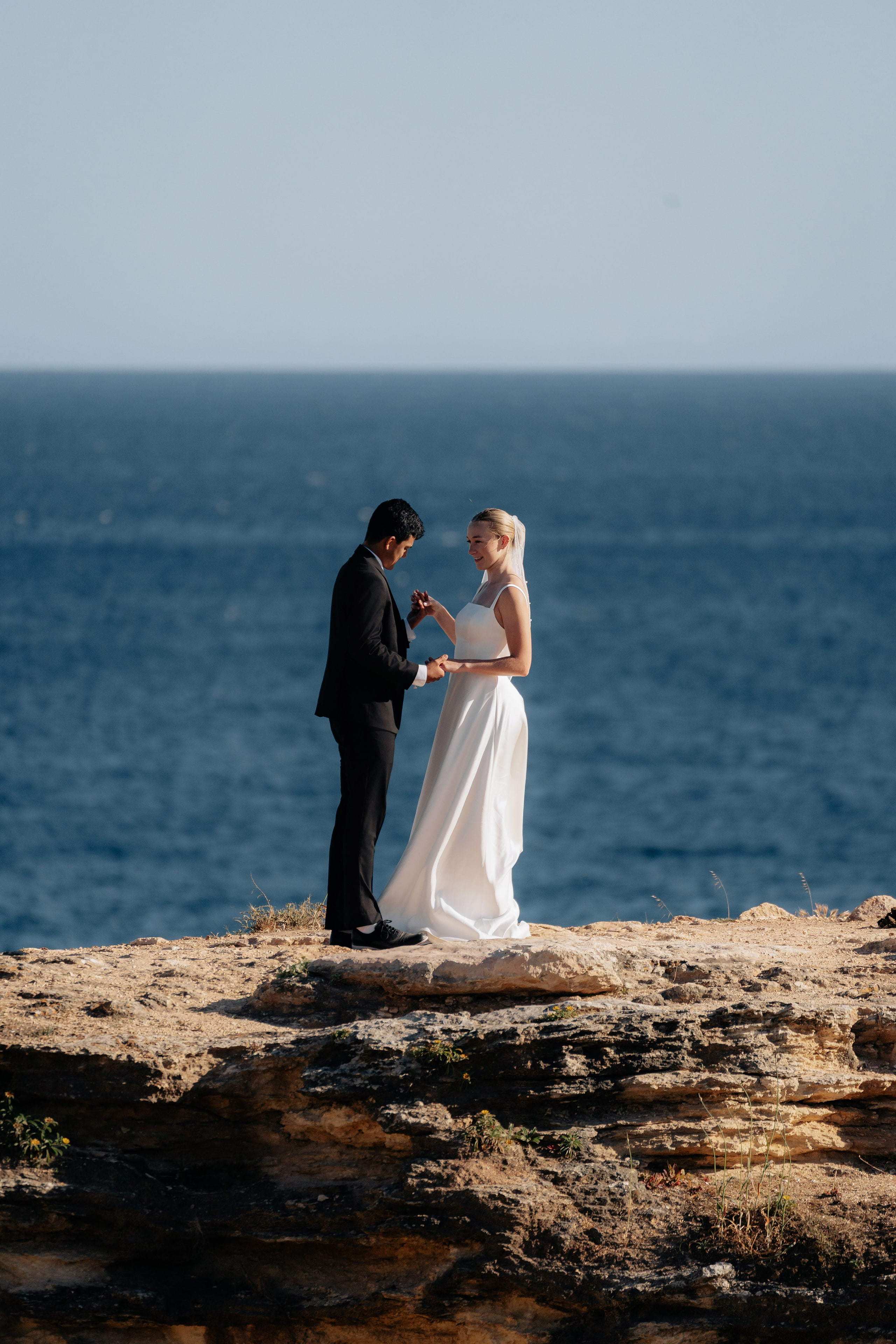 Couple on a rock above the deep blue Atlantic near the arch of Albandeira, Algarve Couple on a rock above the deep blue Atlantic near the arch of Albandeira, Algarve