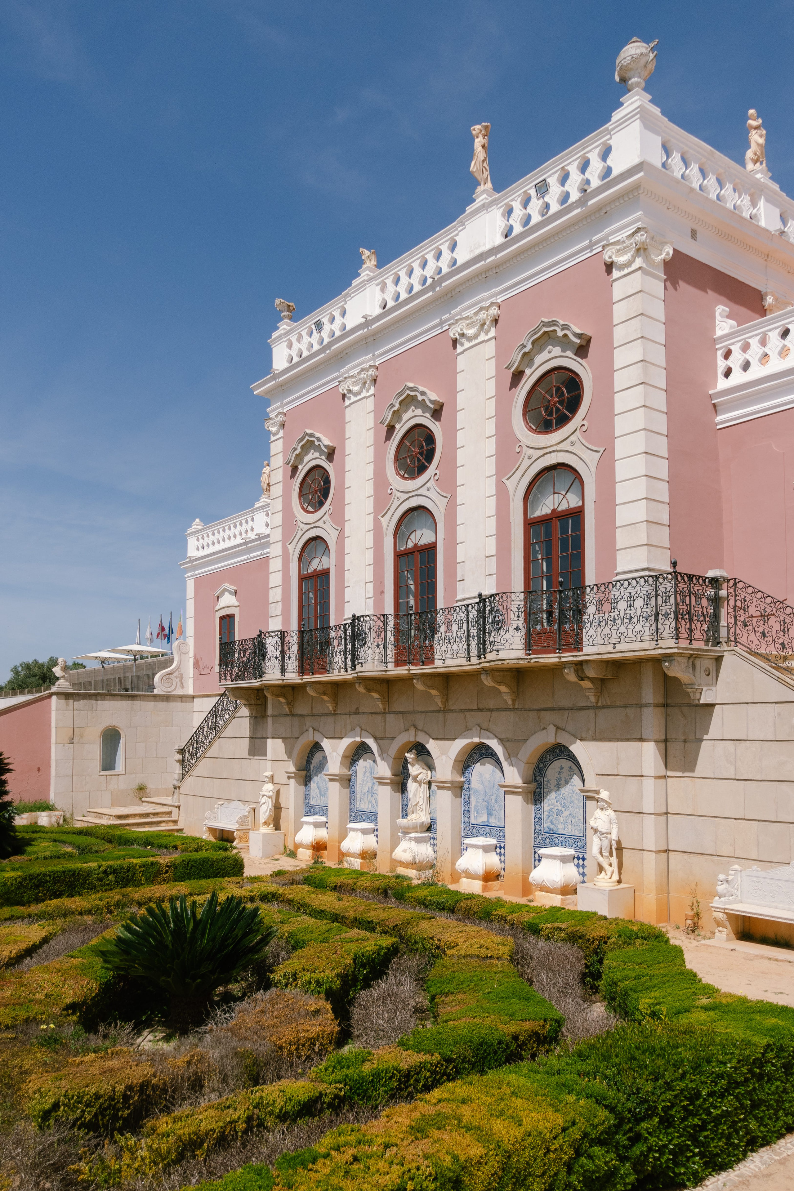 The pink rococo facade of the Palácio de Estoi with its balconies, above the gardens, Algarve The pink rococo facade of the Palácio de Estoi with its balconies, above the gardens, Algarve