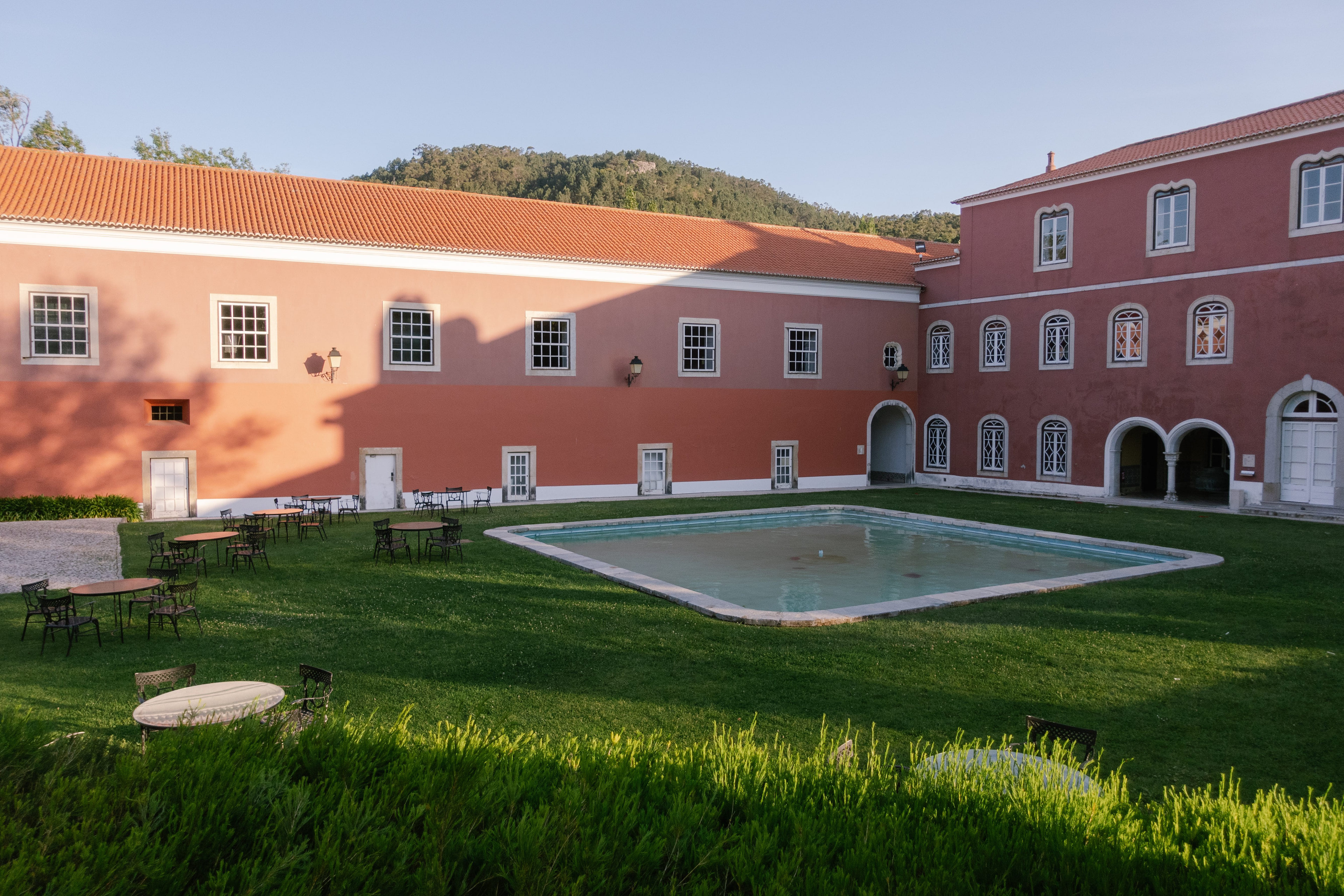 Pink courtyard with arched windows and a pool on the lawn at Penha Longa, Sintra Pink courtyard with arched windows and a pool on the lawn at Penha Longa, Sintra