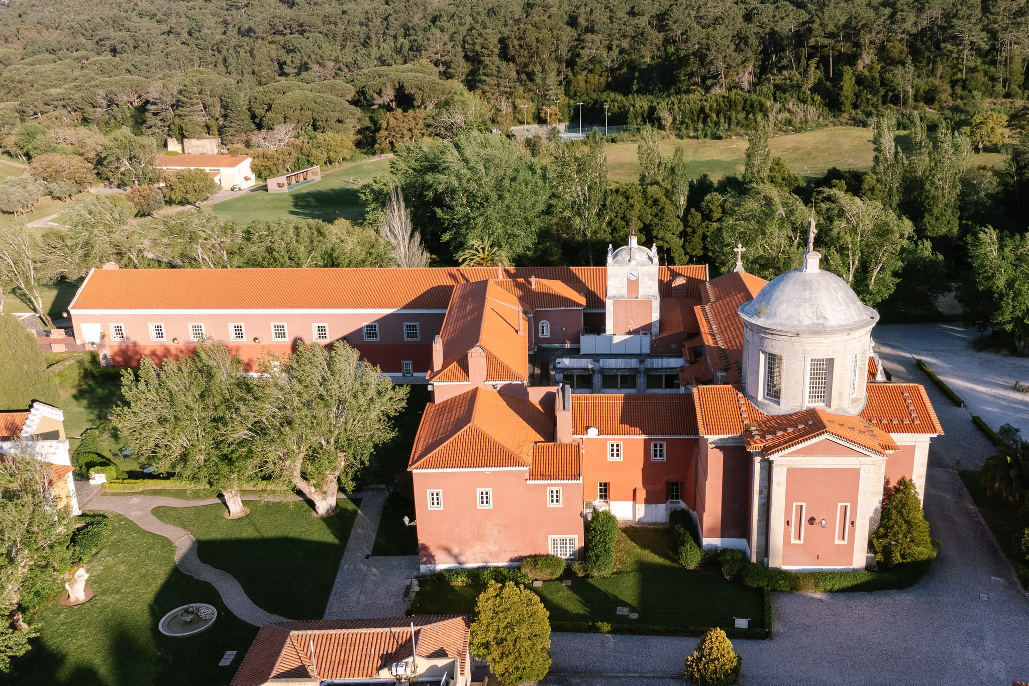 Penha Longa from above: the pink monastery with its domes among the green hills of the Sintra-Cascais Natural Park Penha Longa from above: the pink monastery with its domes among the green hills of the Sintra-Cascais Natural Park