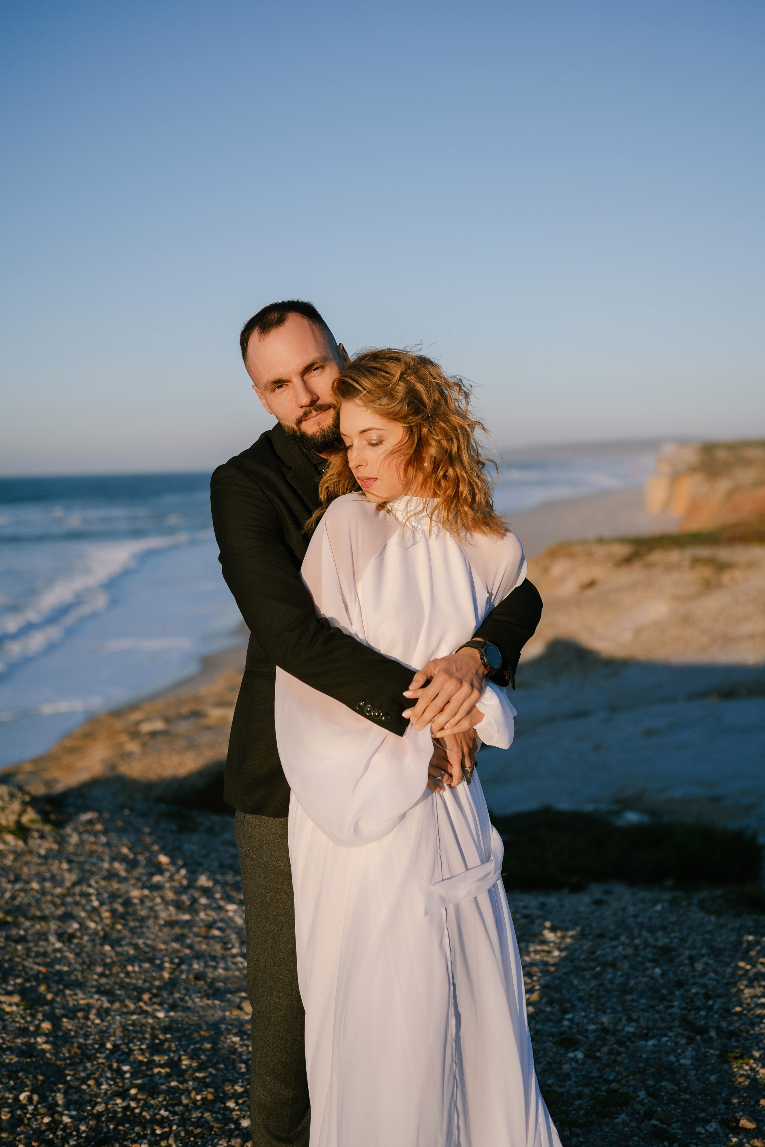 Couple embracing by the sea at Praia del Rey, Portugal