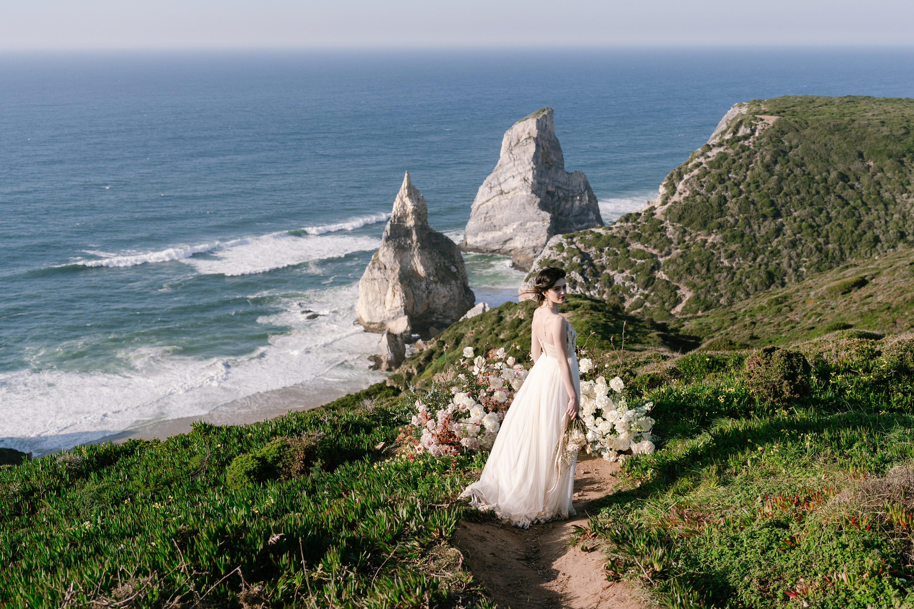Bride on the clifftop above Praia da Ursa with the sea stacks behind her, Sintra coast Bride on the clifftop above Praia da Ursa with the sea stacks behind her, Sintra coast