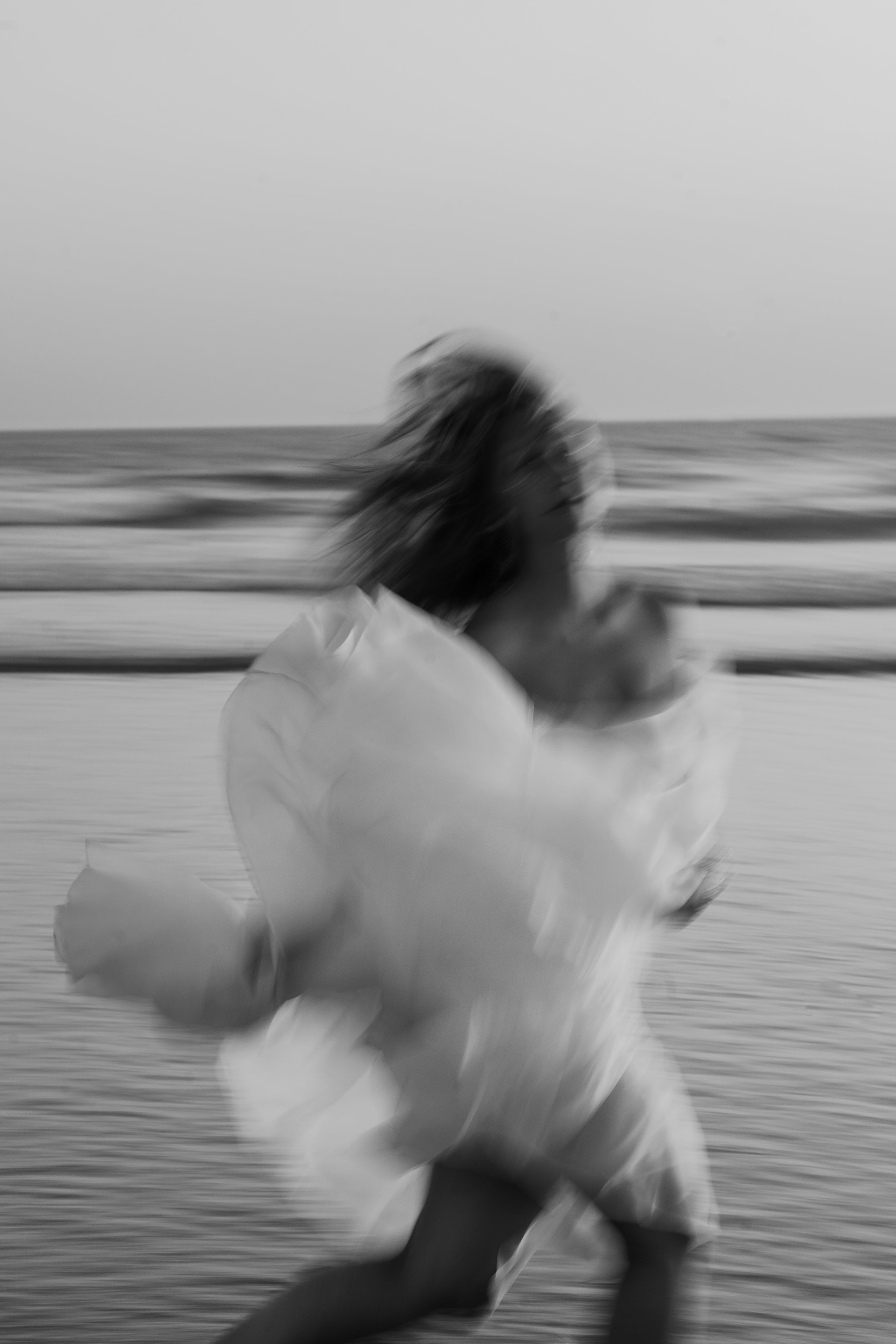 Bride running along Costa da Caparica beach, black and white Bride running along Costa da Caparica beach, black and white