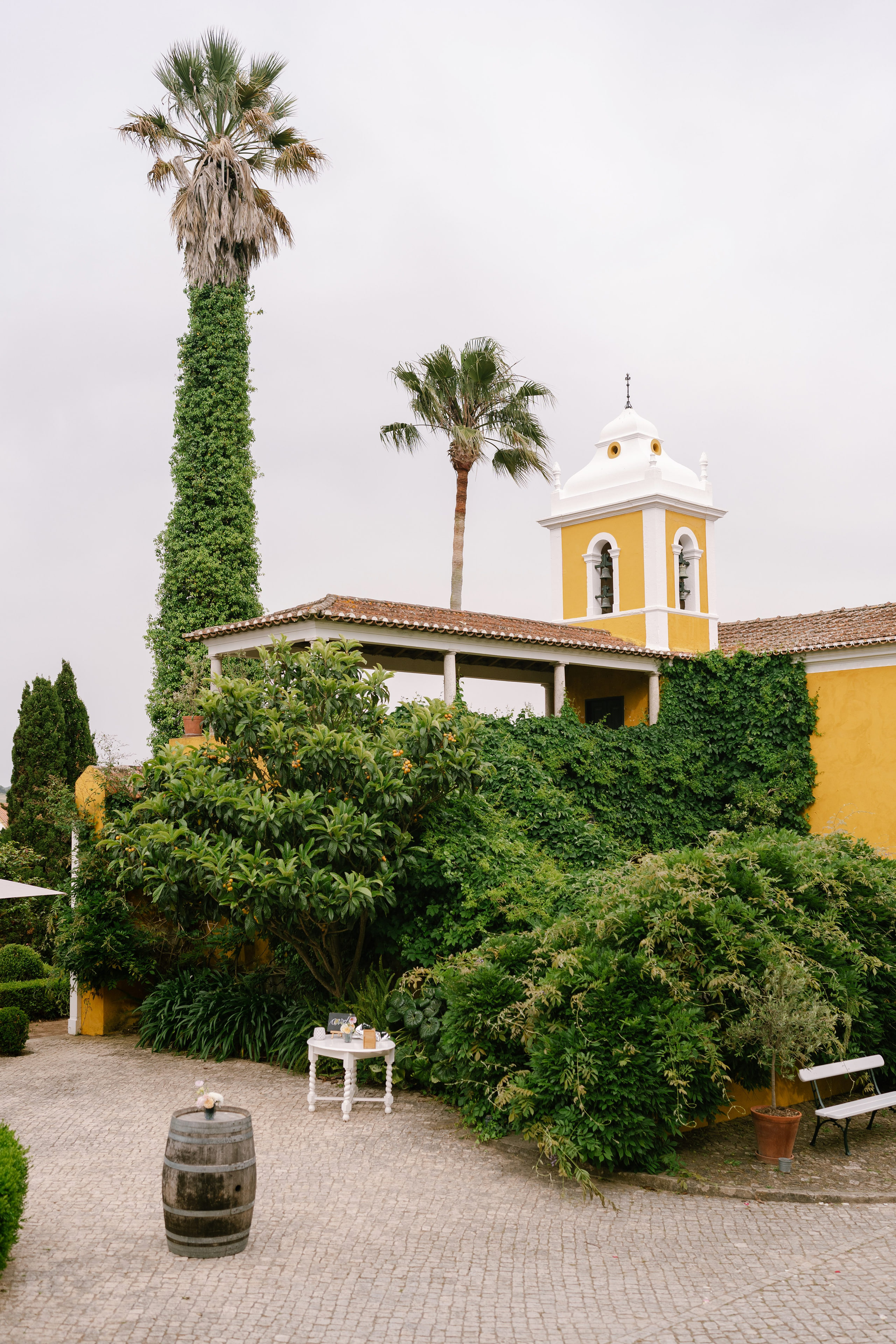 Palm trees and an ivy-covered yellow bell tower in the garden courtyard of Quinta de Sant'Ana, Portugal Palm trees and an ivy-covered yellow bell tower in the garden courtyard of Quinta de Sant'Ana, Portugal